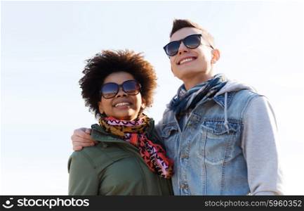 international friendship, relations, tourism, travel and people concept - happy teenage friends or couple in sunglasses hugging outdoors