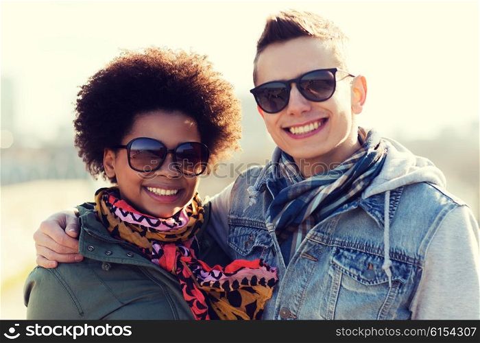 international friendship, relations, tourism, travel and people concept - happy teenage friends or couple in sunglasses hugging outdoors