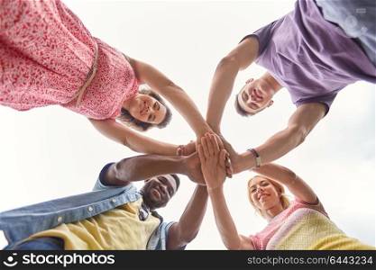 international friendship, unity and people concept - group of happy smiling friends outdoors holding hands. group of happy friends holding hands