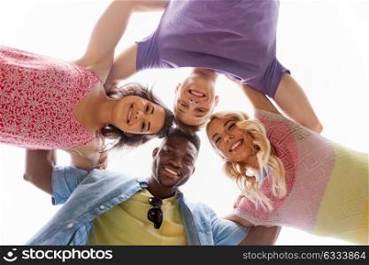international friendship, unity and people concept - group of happy smiling friends outdoors hugging. group of happy friends hugging