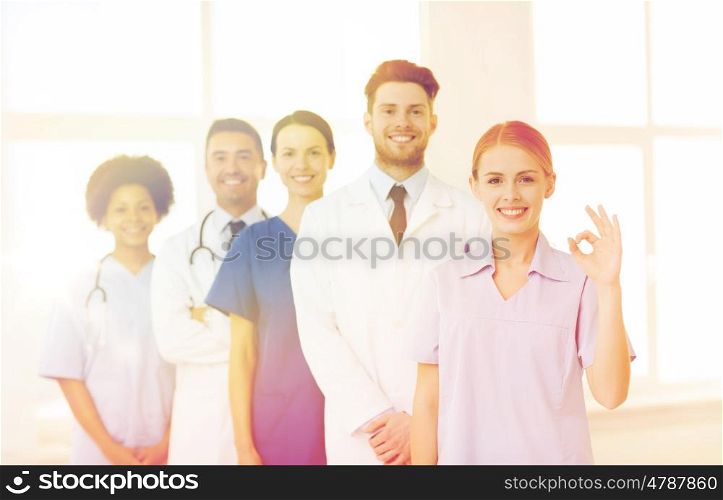 international, profession, people and medicine concept - group of happy doctors and nurses at hospital showing ok hand sign