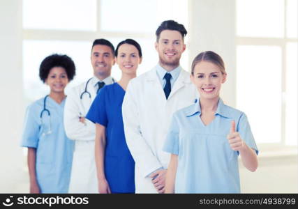 international, profession, people and medicine concept - group of happy doctors and nurses at hospital showing thumbs up gesture. group of doctors and nurses at hospital