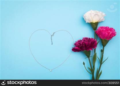International Woman's Day with flowers and heart shape necklace on blue background