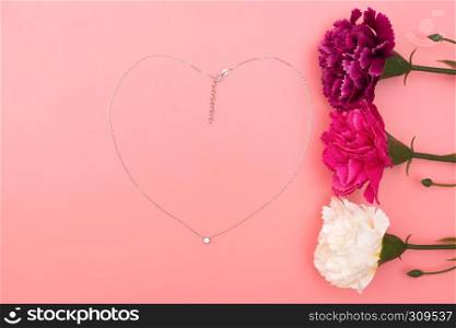 International Woman's Day with flowers and heart shape necklace on pink background