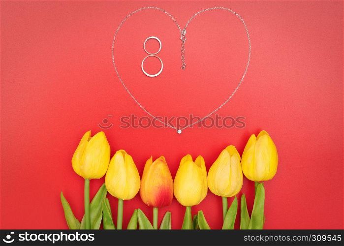 International Woman's Day with flowers and heart shape necklace on red background
