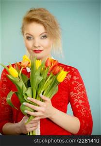 International women day, eight march. Beautiful portrait of pretty woman blonde hair with red yellow tulips, fashion make up, elegant outfit. Mother day. On blue. Pretty woman with red yellow tulips bunch