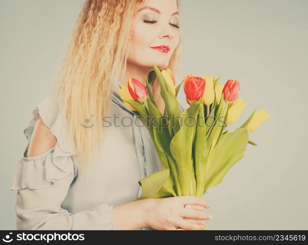 International women day, eight march. Beautiful portrait of pretty woman blonde hair with red yellow tulips, fashion make up. Mother day. Toned image. Pretty woman with red yellow tulips bunch