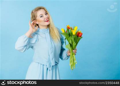 International women day, eight march. Beautiful portrait of pretty woman blonde hair with red yellow tulips, fashion make up, elegant dress. Mother day. On blue. Pretty woman with red yellow tulips bunch