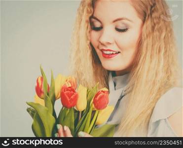 International women day, eight march. Beautiful portrait of pretty woman blonde hair with red yellow tulips, fashion make up. Mother day. Toned image. Pretty woman with red yellow tulips bunch