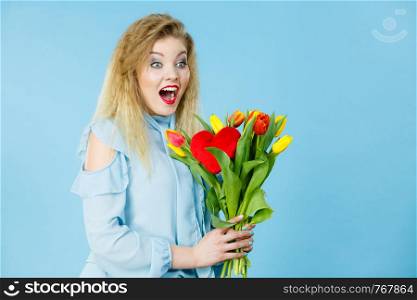 International women day, eight march. Beautiful woman blonde female with red yellow tulips, fashion make up, elegant dress. Positive excited face expression. Mother day. On blue. Pretty woman with red yellow tulips bunch