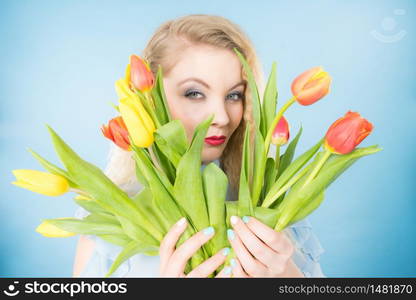 International womens day, eight march. Beautiful portrait of pretty woman blonde hair with red yellow tulips, fashion make up. Mothers day. On blue. Pretty woman with red yellow tulips bunch