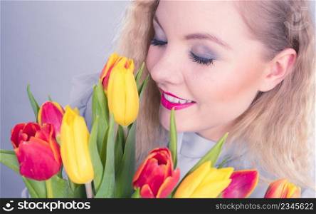 International womens day, eight march. Beautiful portrait of pretty woman blonde hair with red yellow tulips, fashion make up. Mothers day. On grey. Pretty woman with red yellow tulips bunch
