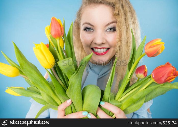 International womens day, eight march. Beautiful portrait of pretty woman blonde hair with red yellow tulips, fashion make up. Mothers day. On blue. Pretty woman with red yellow tulips bunch