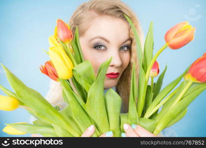 International womens day, eight march. Beautiful portrait of pretty woman blonde hair with red yellow tulips, fashion make up. Mothers day. On blue. Pretty woman with red yellow tulips bunch