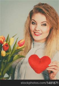 International womensm mothers or valentines day. Beautiful woman blonde hair fashion make up holding tulips bunch and red heart sign. Filtered image. Woman holds tulips and red heart