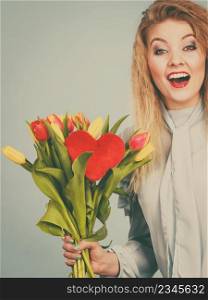 International womensm mothers or valentines day. Beautiful woman blonde hair fashion make up holding tulips bunch and red heart sign. Filtered image. Woman holds tulips and red heart