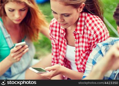 internet addiction, technology and people concept - group of friends with smartphone at camping