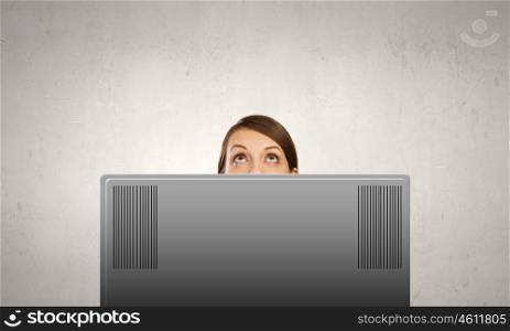 Internet addiction. Young woman looking out above laptop monitor