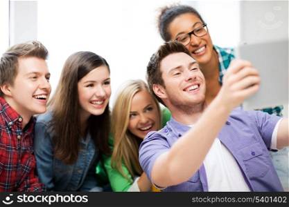 internet and technology concept - group of students making picture with tablet pc