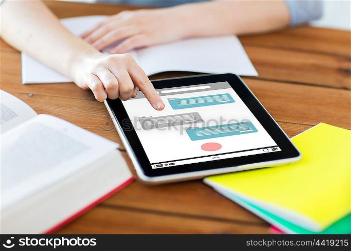 internet communication, education, technology and internet concept - close up of student woman with messenger on tablet pc computer screen and notebook at home