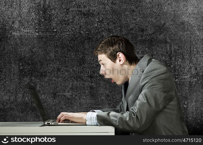 Internet communication. Young man sitting at table and using laptop