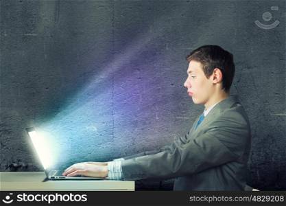 Internet communication. Young man sitting at table and using laptop
