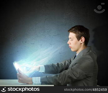 Internet communication. Young man sitting at table and using laptop