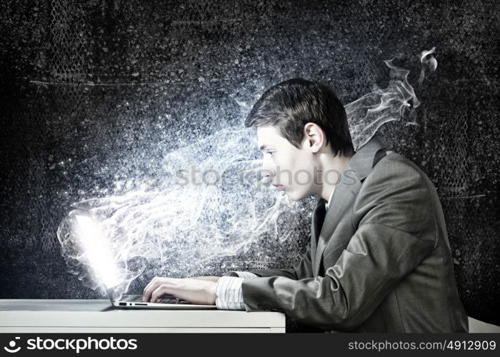 Internet communication. Young man sitting at table and using laptop