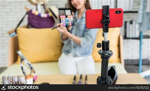 Internet influencer live daily make-up tutorial. Closeup smartphone on tripod to record blogger woman show brush and eyeshadow powder palette. live streaming at home to create content online.