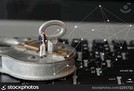 Internet security concept-miniature businessman stand on old key and padlock on laptop computer keyboard