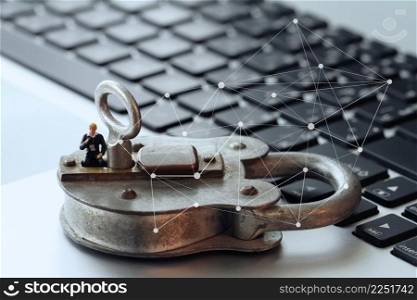 Internet security concept-miniature businessman stand on old key and padlock on laptop computer keyboard