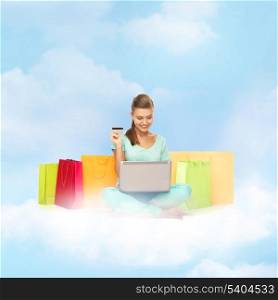 internet shopping and future technology concept - woman with laptop, shopping bags and credit card on the cloud