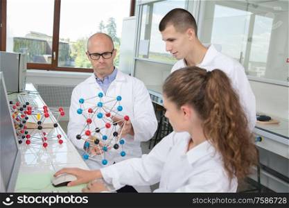 interns in the lab with atoms model