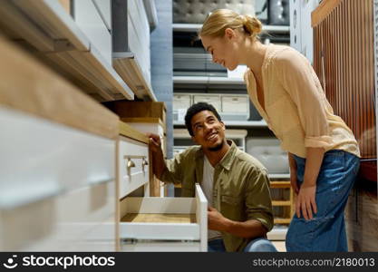 Interracial couple choosing new cabinets kitchen furniture in store looking at details. Couple choosing new kitchen furniture in shop