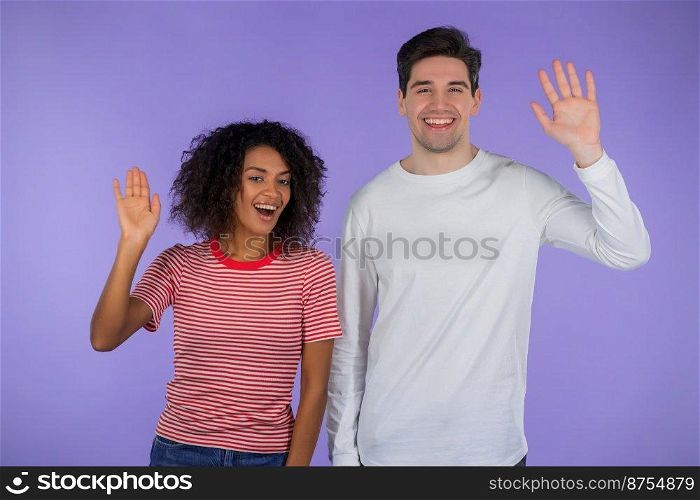 Interracial friendly couple - white man and african woman waving hands - hello. Greeting, say Hi to camera on purple studio background. High quality photo. Interracial friendly couple - white man and african woman waving hands - hello. Greeting, say Hi to camera on purple studio background.