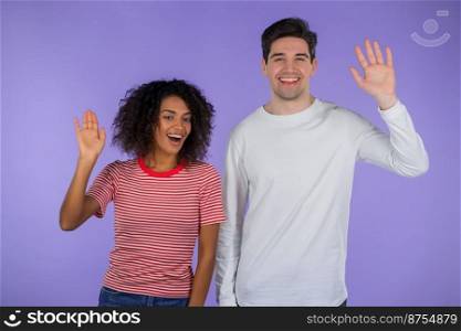 Interracial friendly couple - white man and african woman waving hands - hello. Greeting, say Hi to camera on purple studio background. High quality photo. Interracial friendly couple - white man and african woman waving hands - hello. Greeting, say Hi to camera on purple studio background.