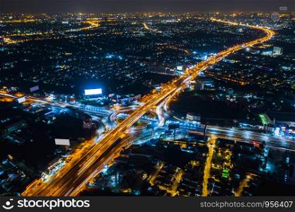 intersection with the motorway freeway highway for logistics business transportation vehicle in thailand long exposure shot at night aerial top view from drone