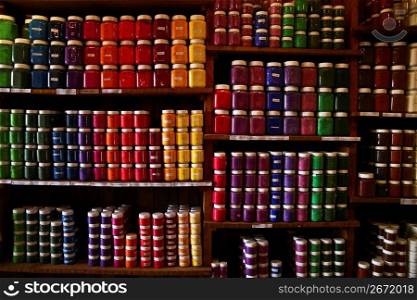 Inventory rows of colorful paint in jars on shelves in store