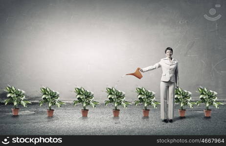 Invest right to get income. Young businesswoman watering green plant with can