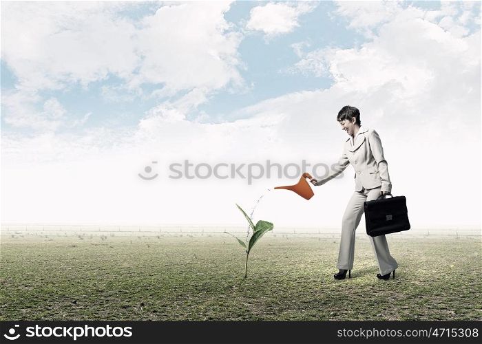 Invest right to get income. Young businesswoman watering green plant with can