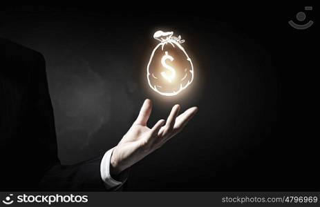 Invest your money right. Hand of businessman holding money bag symbol on dark background