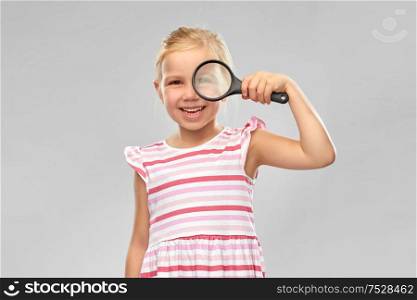investigation, discovery and vision concept - happy girl looking through magnifying glass over grey background. happy girl looking through magnifying glass