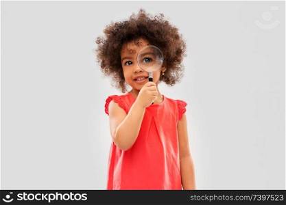 investigation, discovery and vision concept - happy little african american girl looking through magnifying glass over grey background. african girl looking through magnifying glass