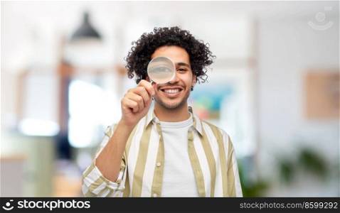 investigation, discovery and vision concept - happy man looking through magnifying glass over office background. happy man looking through magnifying glass