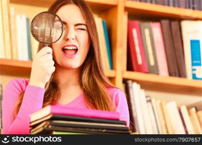 Investigation exploration education concept. Closeup intelligent funny student girl in library, woman holding magnifying glass loupe