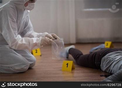 investigation, forensic examination and people concept - criminalist collecting evidence of murder at crime scene (staged photo). criminalist collecting crime scene evidence. criminalist collecting crime scene evidence