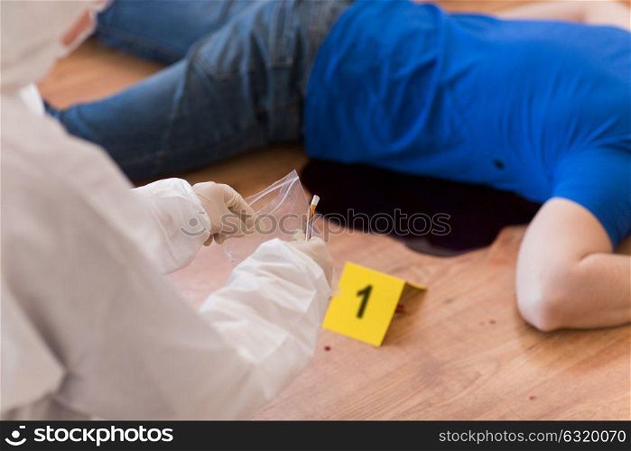 investigation, forensic examination and people concept - criminalist collecting evidence of murder at crime scene (staged photo). criminalist collecting crime scene evidence