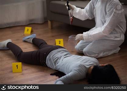 investigation, forensic examination and people concept - criminalist collecting evidence of murder at crime scene (staged photo). criminalist collecting crime scene evidence