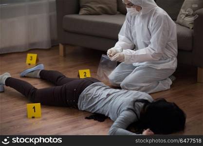 investigation, forensic examination and people concept - criminalist collecting evidence of murder at crime scene (staged photo). criminalist collecting crime scene evidence. criminalist collecting crime scene evidence