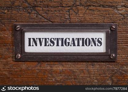 investigations - file cabinet label, bronze holder against grunge and scratched wood